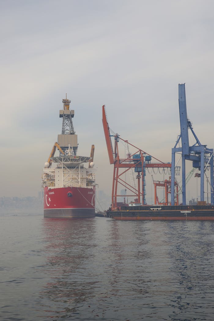 Cargo ship moored at a bustling industrial port with towering cranes.